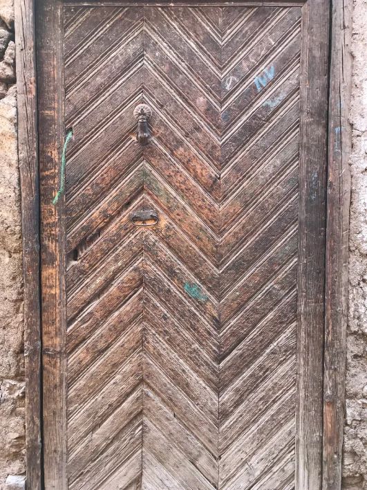 Weathered chevron-planked wooden door with an iron knocker